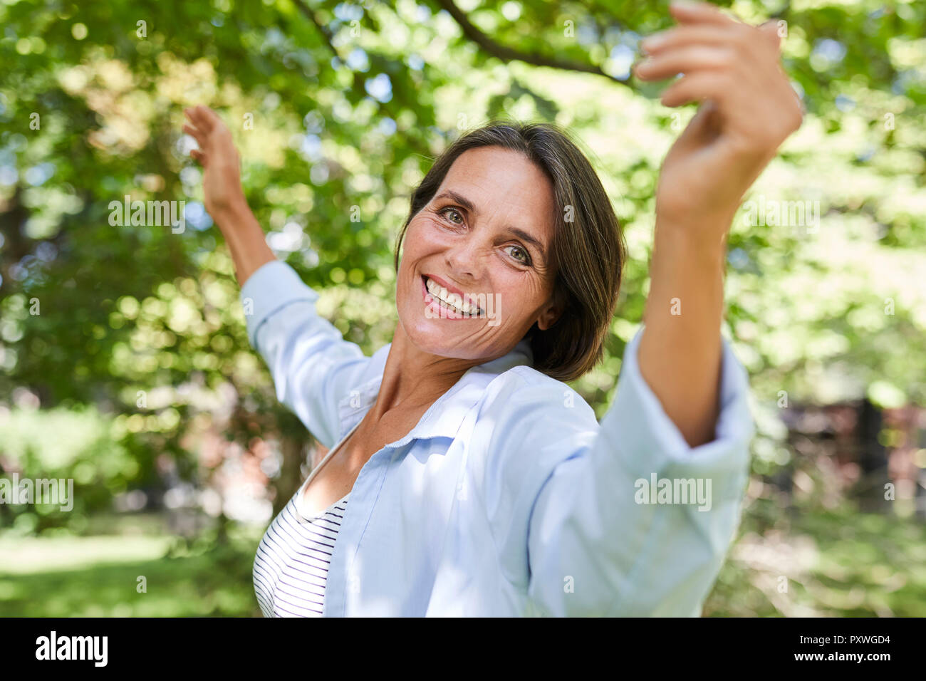 Portrait of smiling mature woman dancing in nature Banque D'Images