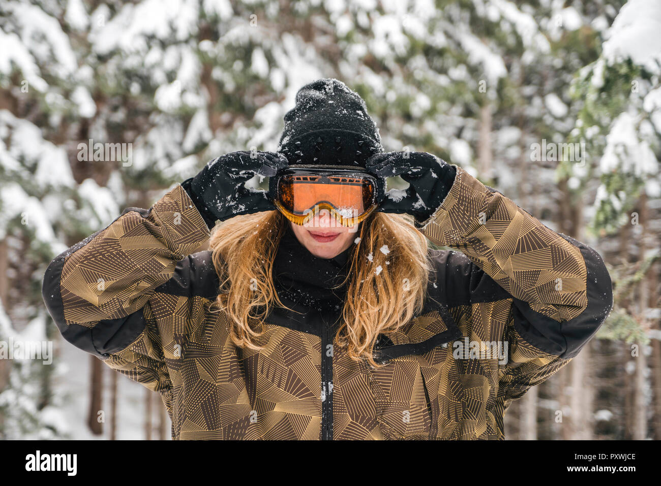 Jeune femme mettre sur lunettes de ski en forêt d'hiver Banque D'Images