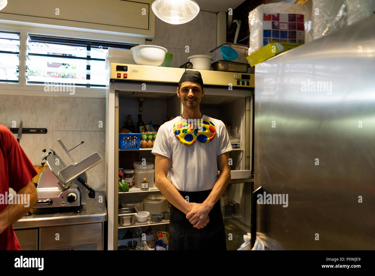 Portrait de drôle de clown pizza baker portant nœud papillon en cuisine Banque D'Images