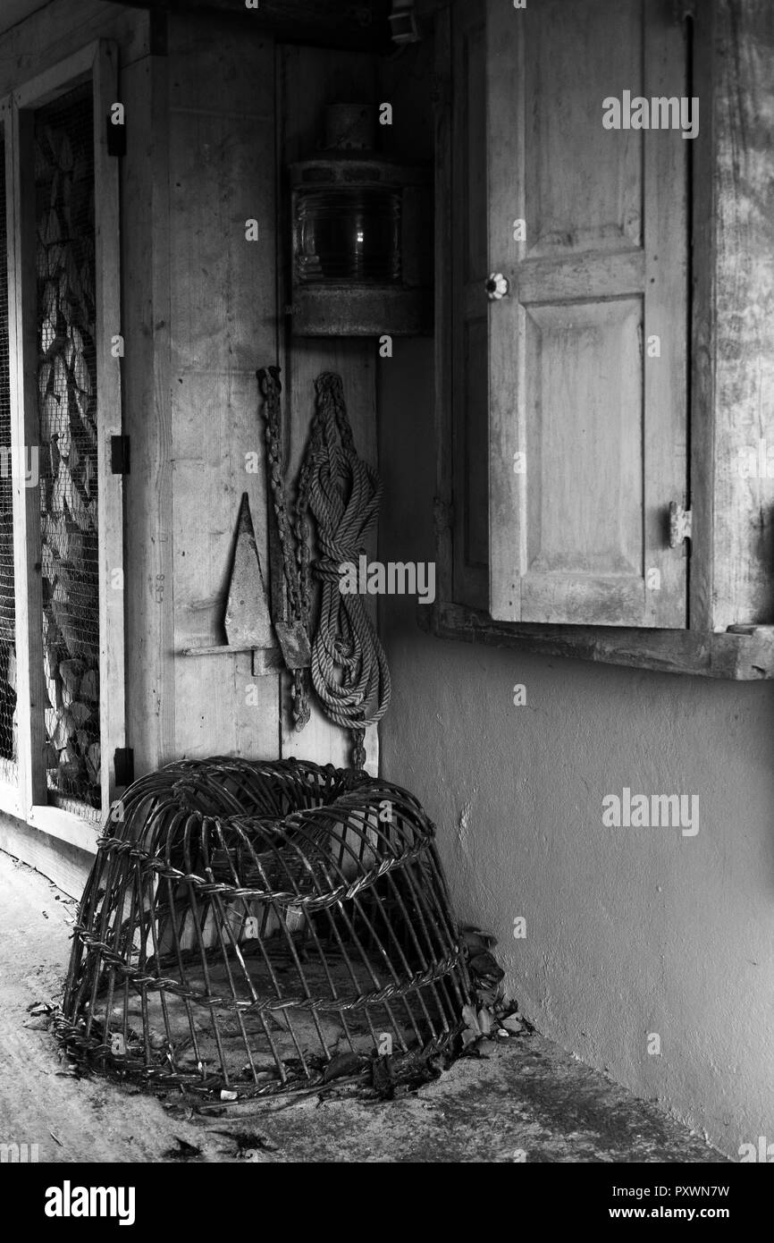 Le noir et blanc de l'allée à côté d'une chambre montrant lobster pot, corde, anchor, navires lampe et un tas de bois. Banque D'Images