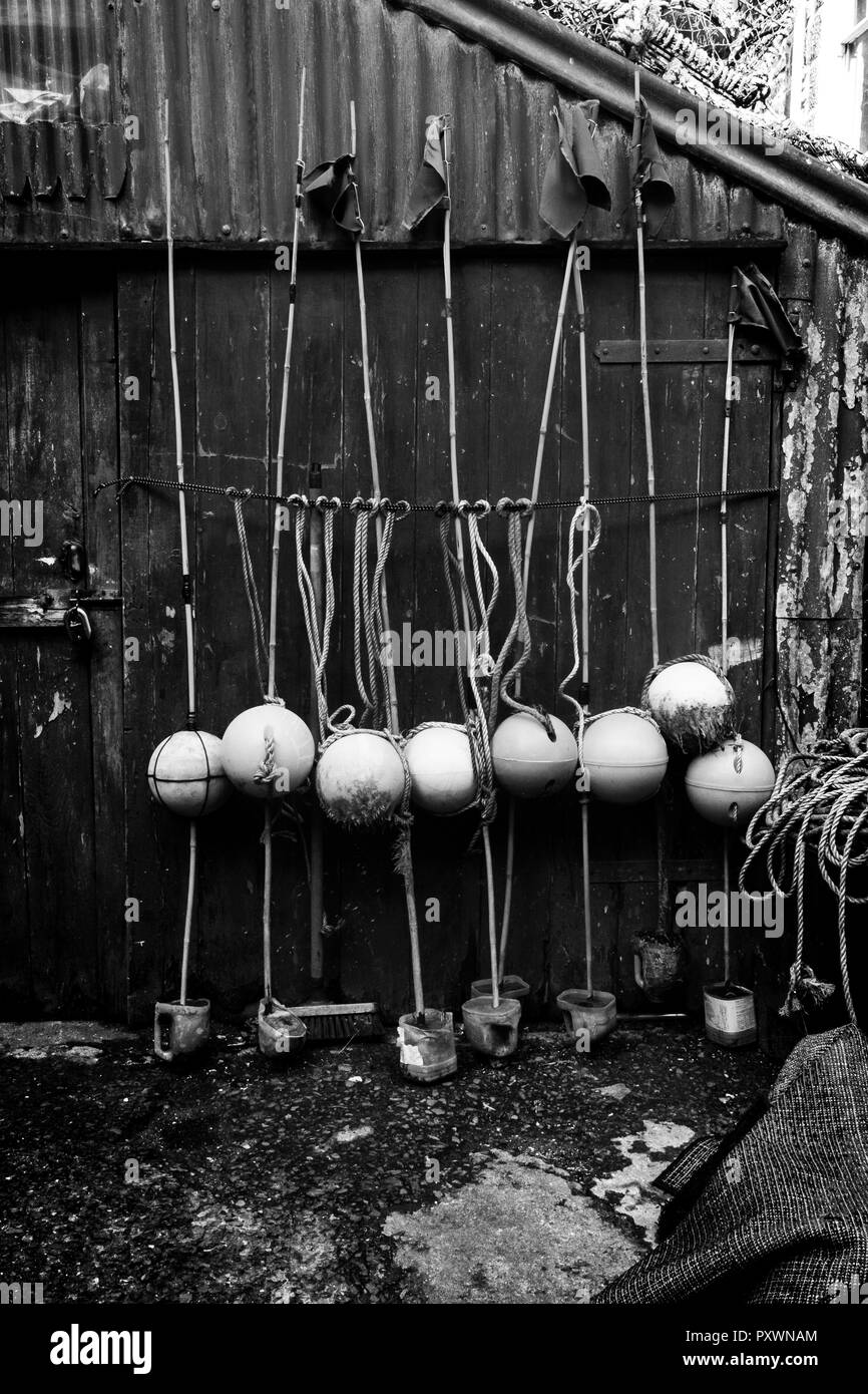 Plusieurs bouées de pêche et une pile de casiers à homard sur un vieux hangar de tôle ondulée peinte en vert, à la recherche et intemporel unkempt Banque D'Images