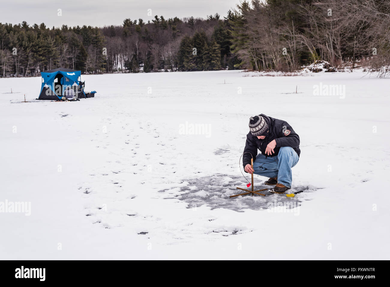 Un homme à la pêche sur glace sur l'Étang gelé à Grafton State Park dans l'État de New York. Banque D'Images