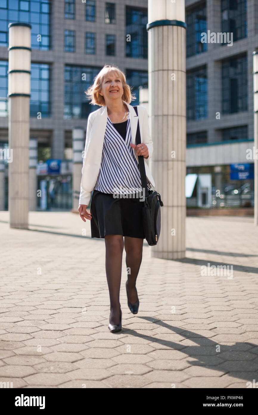 Happy businesswoman est de marcher à l'extérieur de l'entreprise bâtiment. Banque D'Images