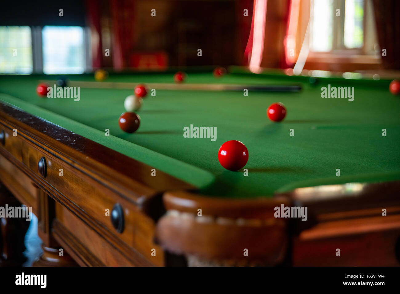 Boule de billard rouge vif, profondeur de champ, à l'avant sur un corner pocket, avec le reste du tableau, cue et boules in soft focus. Banque D'Images
