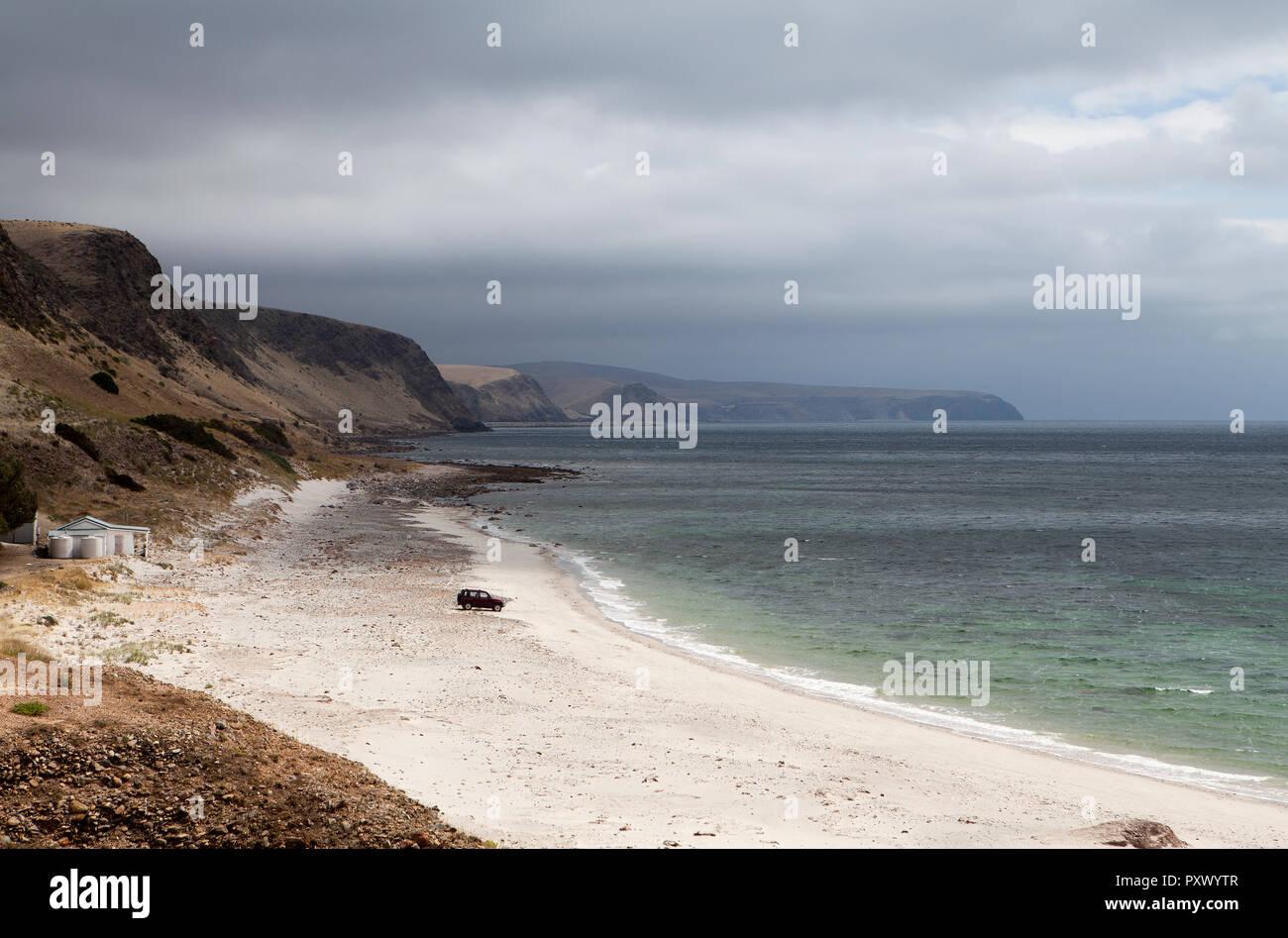 Une plage avec un véhicule stationné sur une plage. Le ciel est orageux, mais la plage est au soleil. Les tournières faible s'évanouissent dans la distance à distance. Banque D'Images