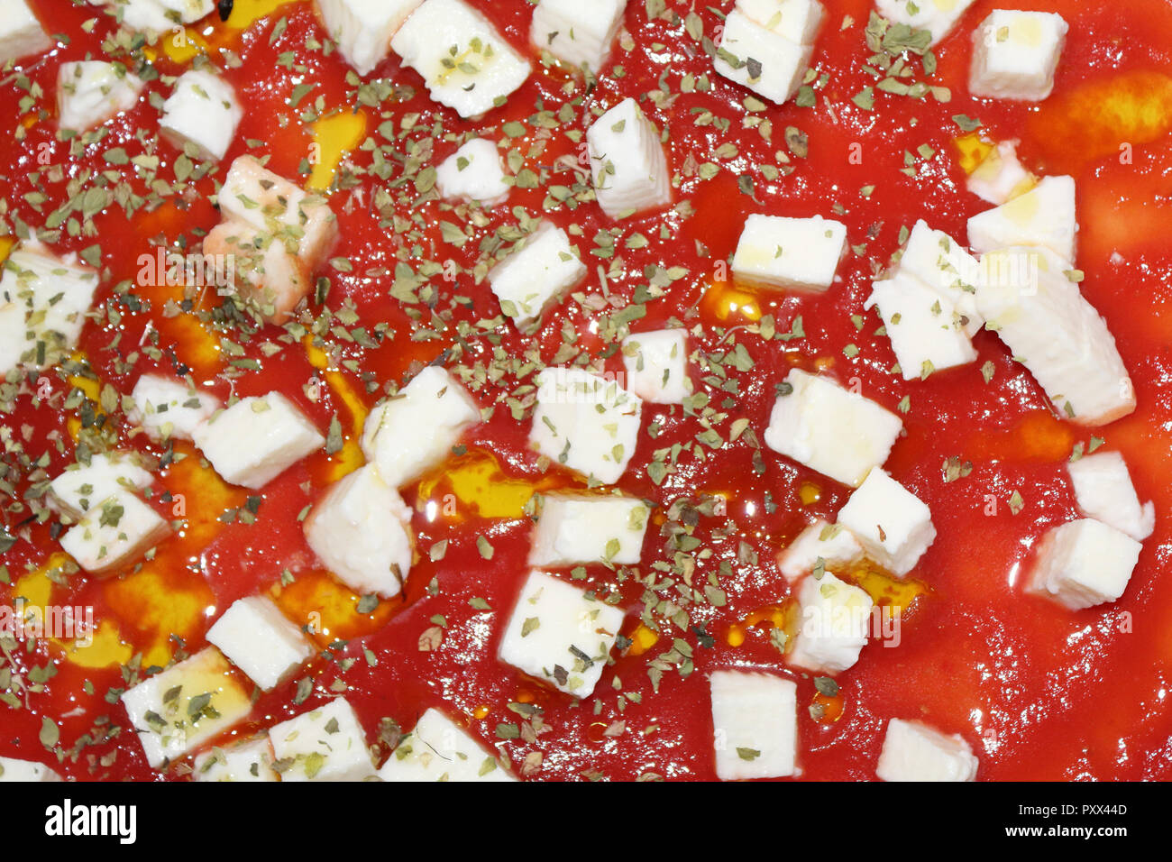 Une vue étroite de matières de la pizza, avec des dés de tomate, mozzarella et origan, avant d'être cuit dans un four, typique de la cuisine italienne Banque D'Images