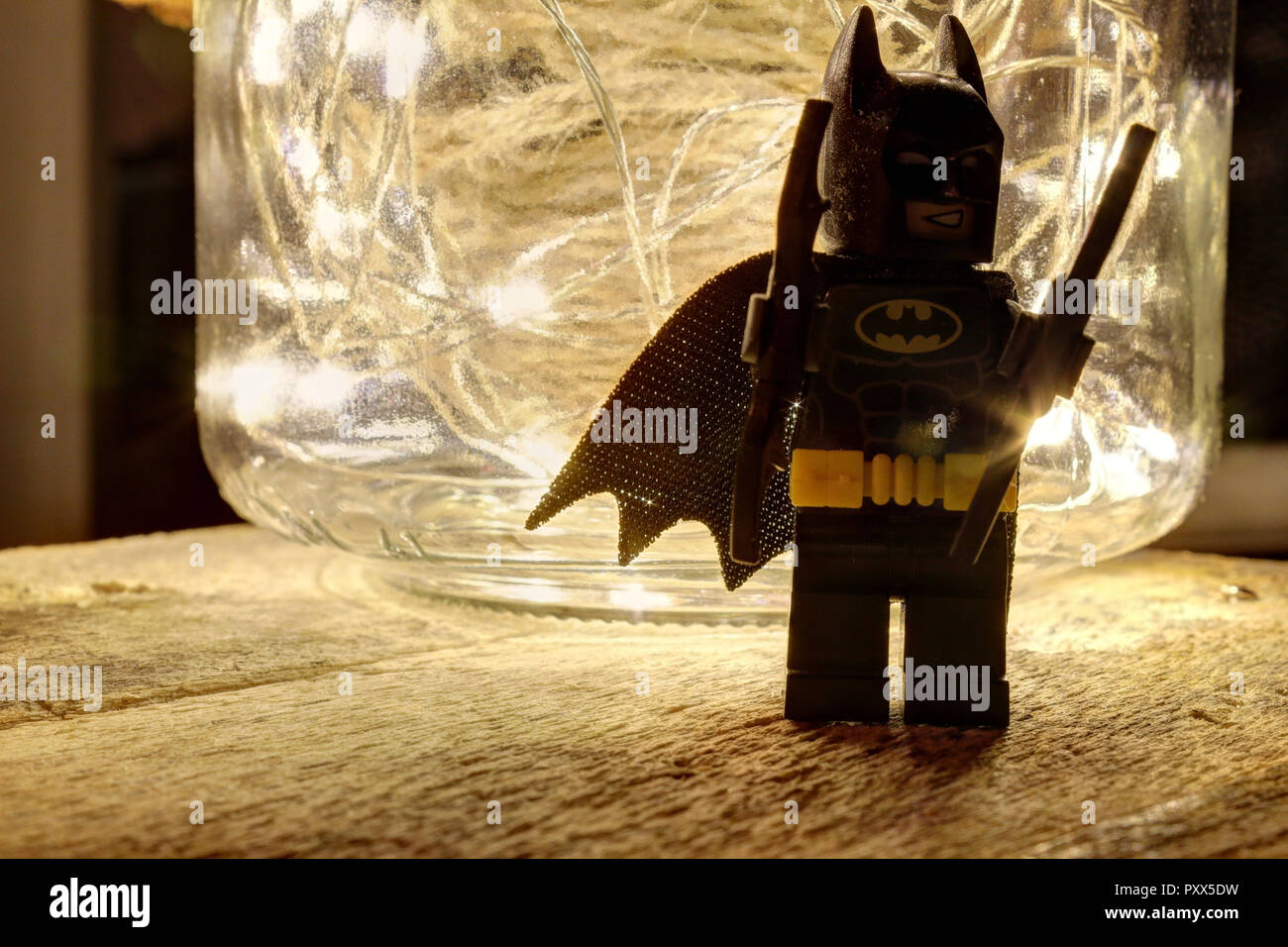 Une nature morte composition avec LEGO Batman, un bocal en verre avec un couvercle en cuir rempli d'une corde de chanvre et quelques voyants lumineux qui brille sur un bois brut Banque D'Images