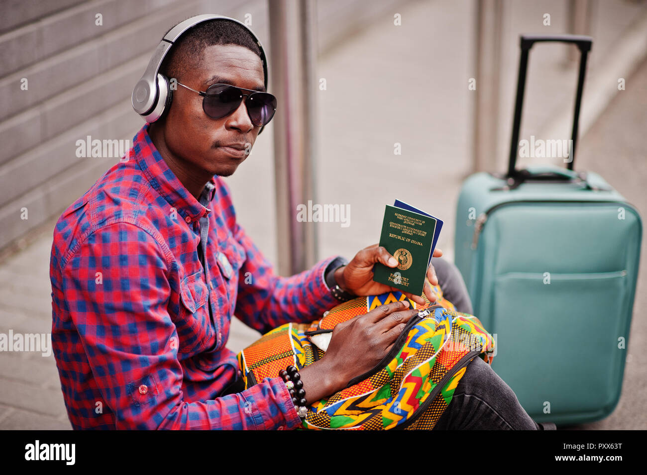 African American man en chemise à carreaux, lunettes de soleil et  d'écouteurs avec valise et sac à dos holding Ghana passeport. Homme noir  traveler Photo Stock - Alamy