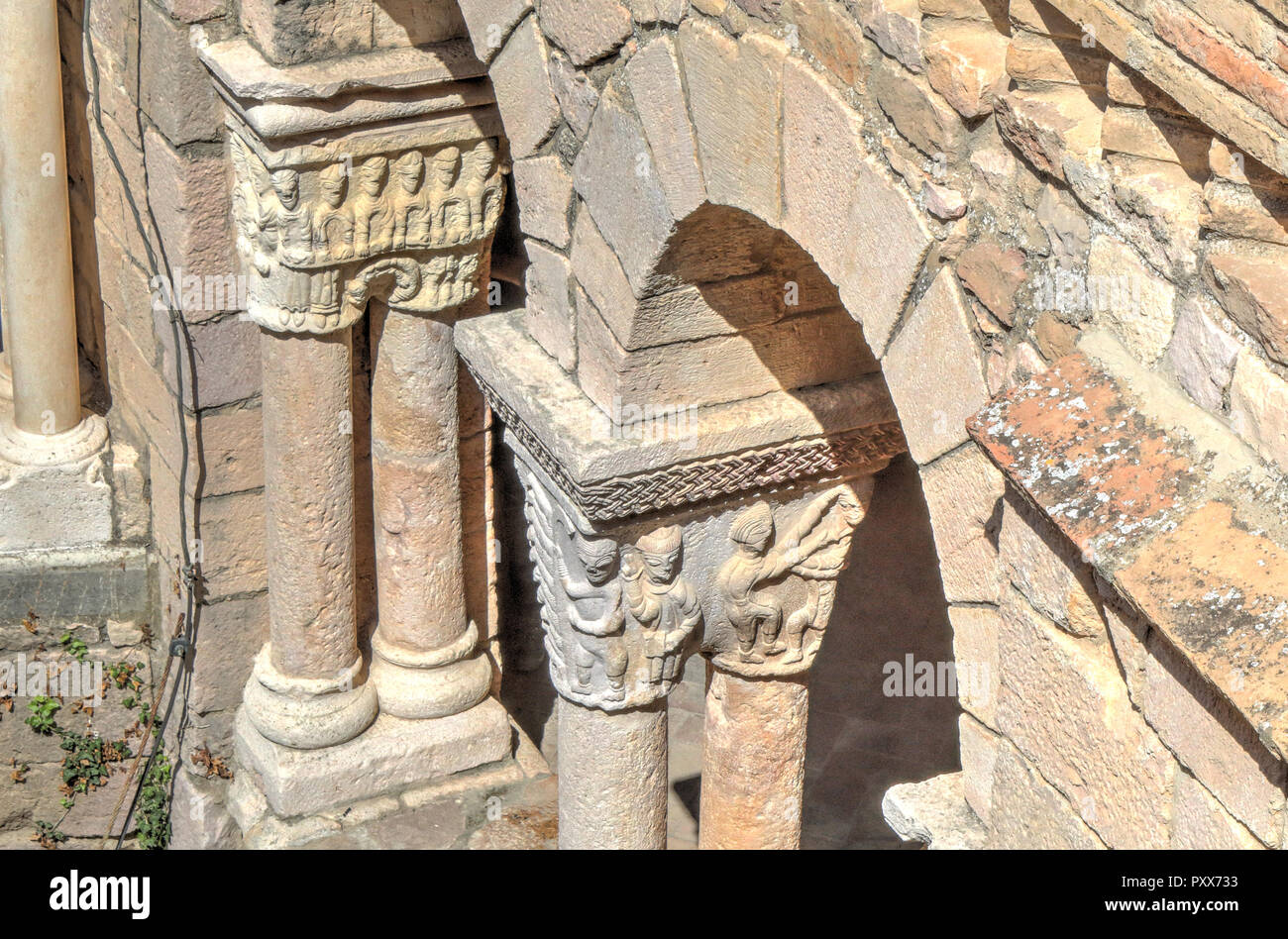 Arches arrondies romane avec chapiteaux sculptés en bas-reliefs de figures humaines, au cours d'une journée ensoleillée dans l'Alquezar Collegiate, Espagne Banque D'Images