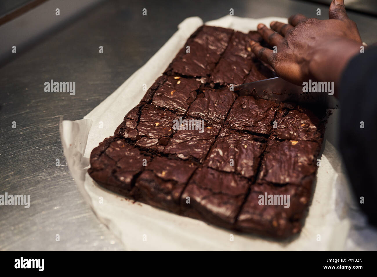 Couper en carrés brownies Baker dans une cuisine cafe Banque D'Images