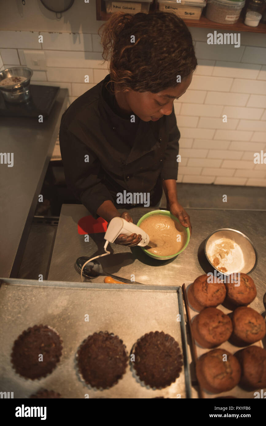 Mélanger la pâte à gâteau Baker dans une cuisine commerciale Banque D'Images