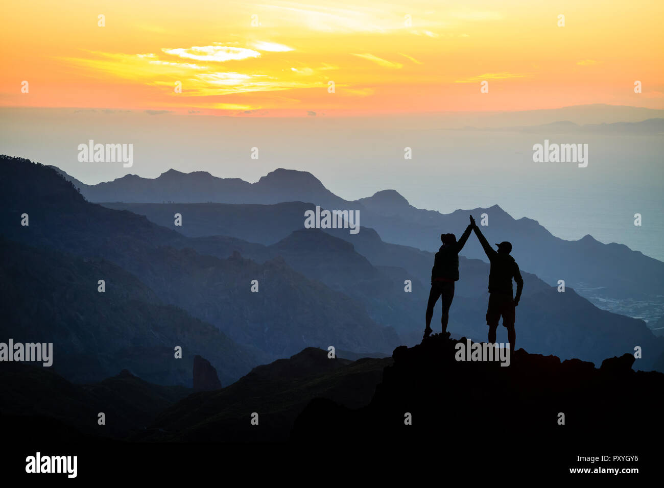 Couple d'équipe aide aide confiance, silhouette succès dans les montagnes. Équipe d'alpinistes l'homme et de la femme. Les randonneurs célébrer avec les mains en l'air, aider chaque ot Banque D'Images