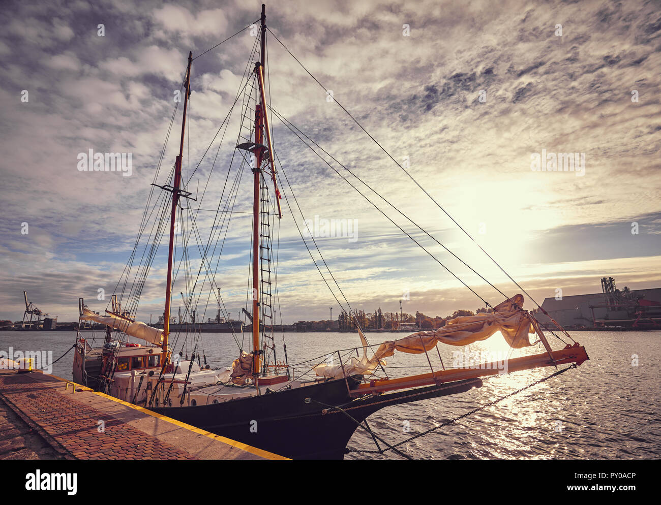 Ancienne goélette amarrée dans un port au lever du soleil, aux teintes de couleur photo. Banque D'Images