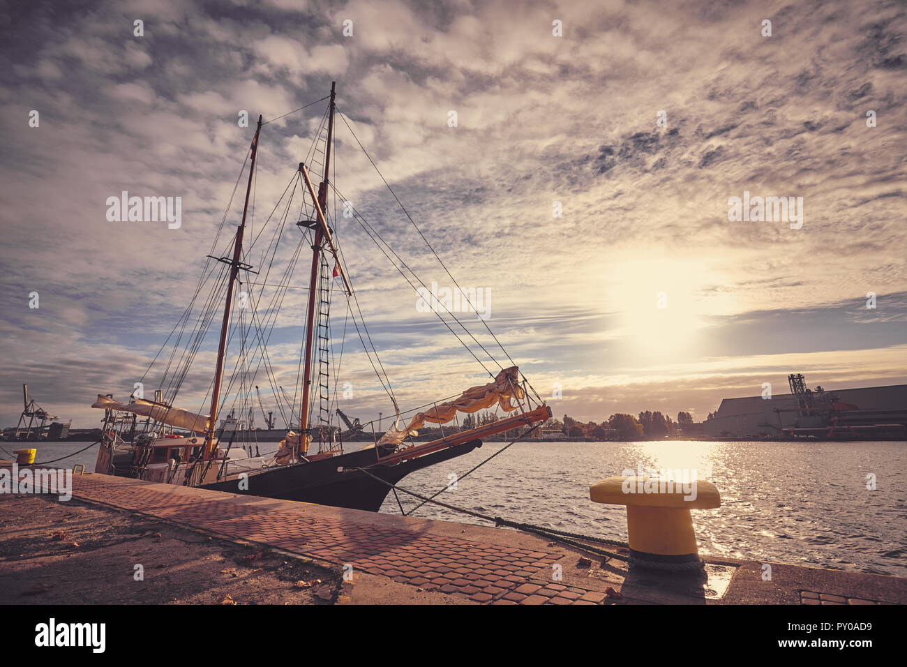 Ancienne goélette amarrée dans un port au lever du soleil, aux teintes de couleur photo. Banque D'Images