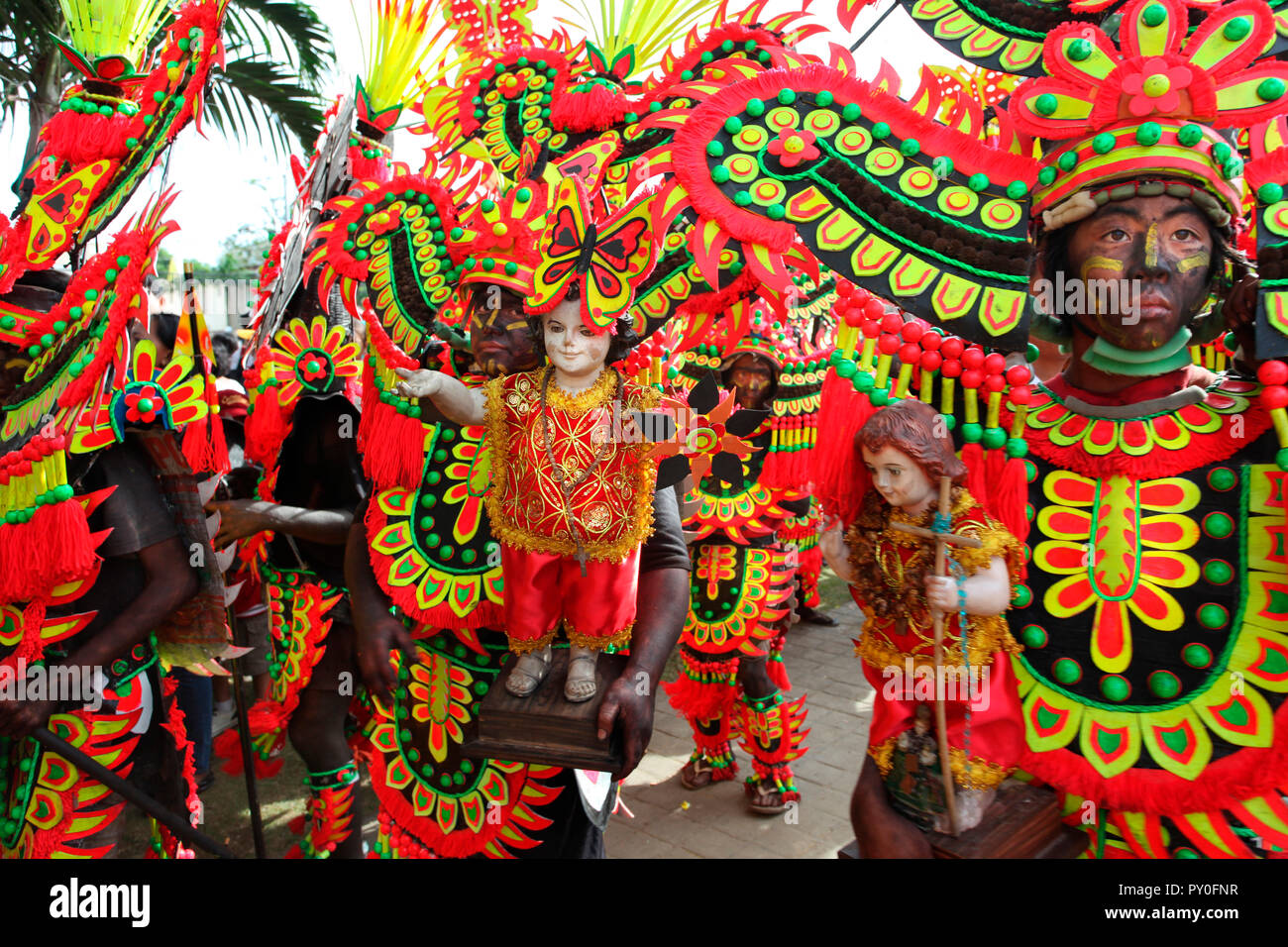 Les gens avec des traînées noires visages dans des costumes tribaux holding Jésus enfant au festival Atihan figurines Ati, Kalibo, Aklan, Philippines, l'île de Panay Banque D'Images