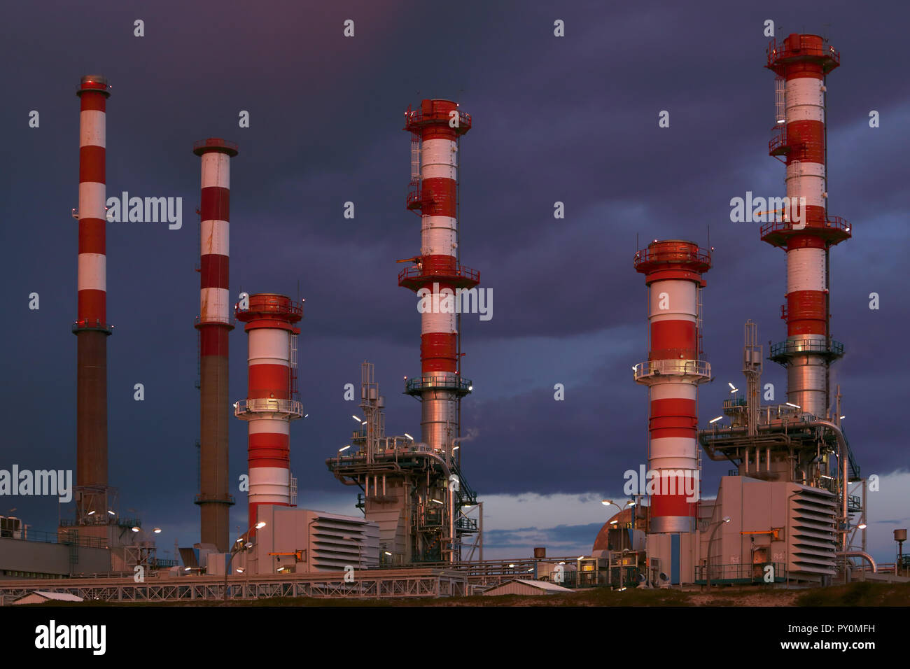 Une partie des nombreuses cheminées d'une grande raffinerie de pétrole de la centrale et dans un ciel couvert nuit Banque D'Images