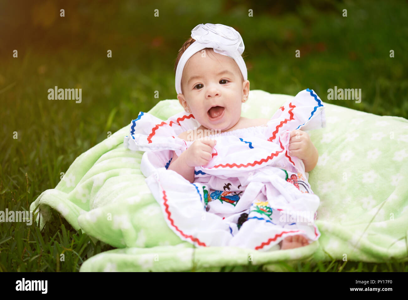 Bébé fille petit mignon assis sur fond d'herbe verte Banque D'Images