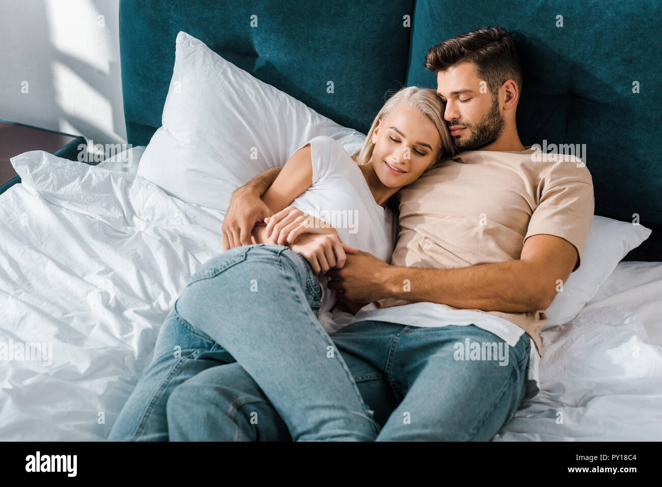 Jeune couple hugging et dormir sur lit dans la chambre Banque D'Images