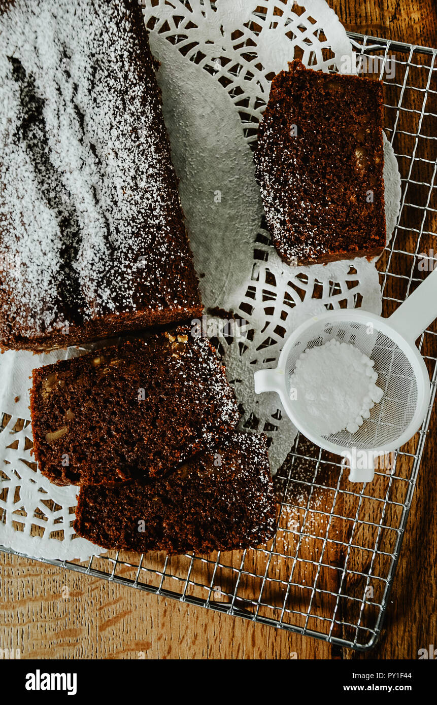 Gateau Au Chocolat Avec Des Noix A L Interieur Coupe En Tranches Sur Une Grille Un Mini Tamis Avec Du Sucre En Poudre Directement Au Dessus De Table En Bois Arriere Plan Photo Stock Alamy
