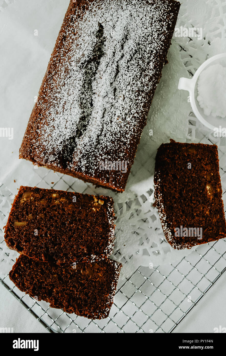 Gateau Au Chocolat Avec Des Noix A L Interieur Coupe En Tranches Sur Une Grille Un Mini Tamis Avec Du Sucre En Poudre Directement Au Dessus Fond Blanc Photo Stock Alamy