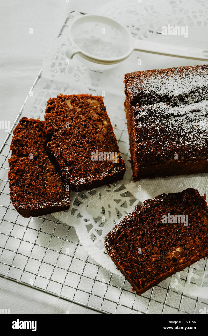 Gateau Au Chocolat Avec Des Noix A L Interieur Coupe En Tranches Sur Une Grille Un Mini Tamis Avec Du Sucre En Poudre Directement Au Dessus Fond Blanc Photo Stock Alamy