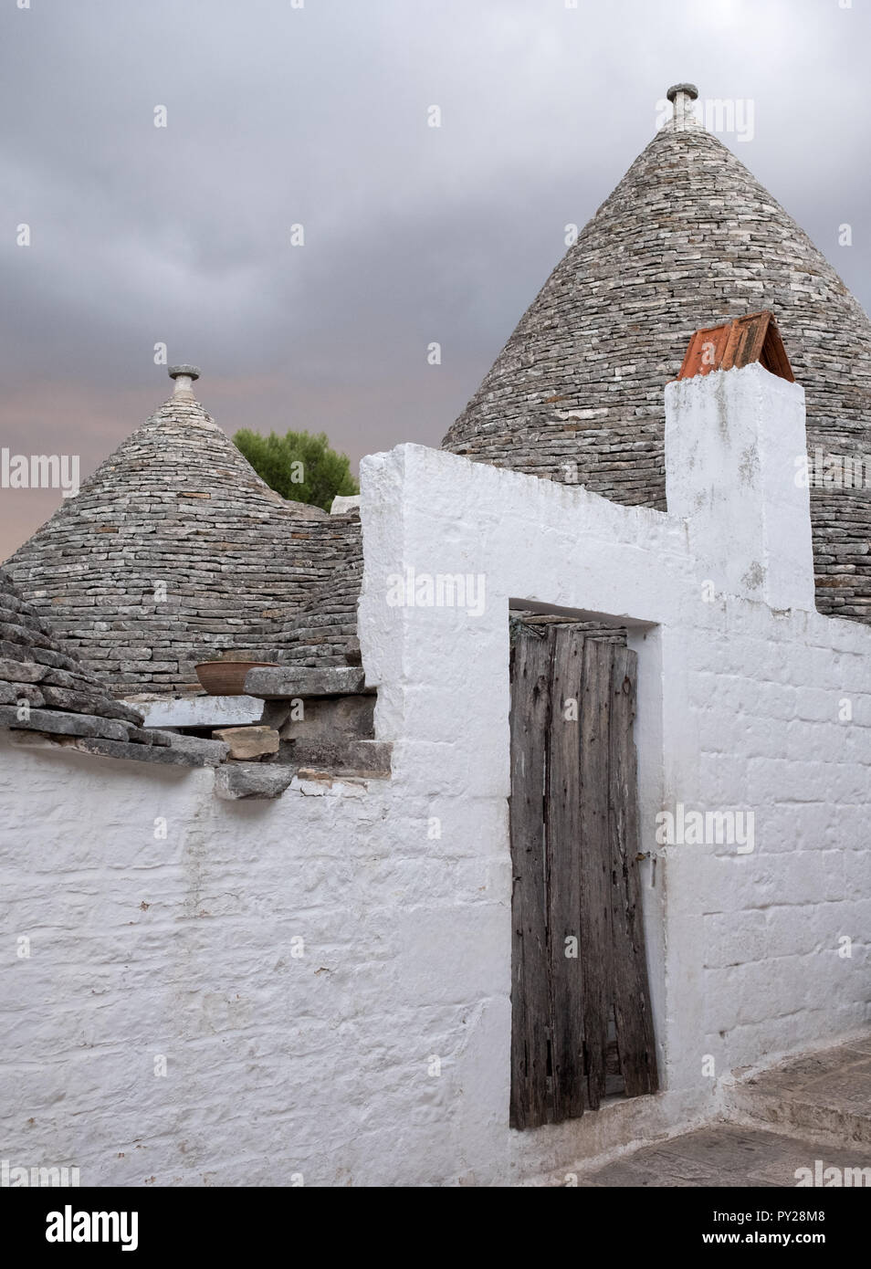 Alberobello, Italie. Au toit conique blanchis à la maison wahsed trulli derrière un mur blanc, dans la ville de Alberobello dans les Pouilles, Italie du Sud Banque D'Images