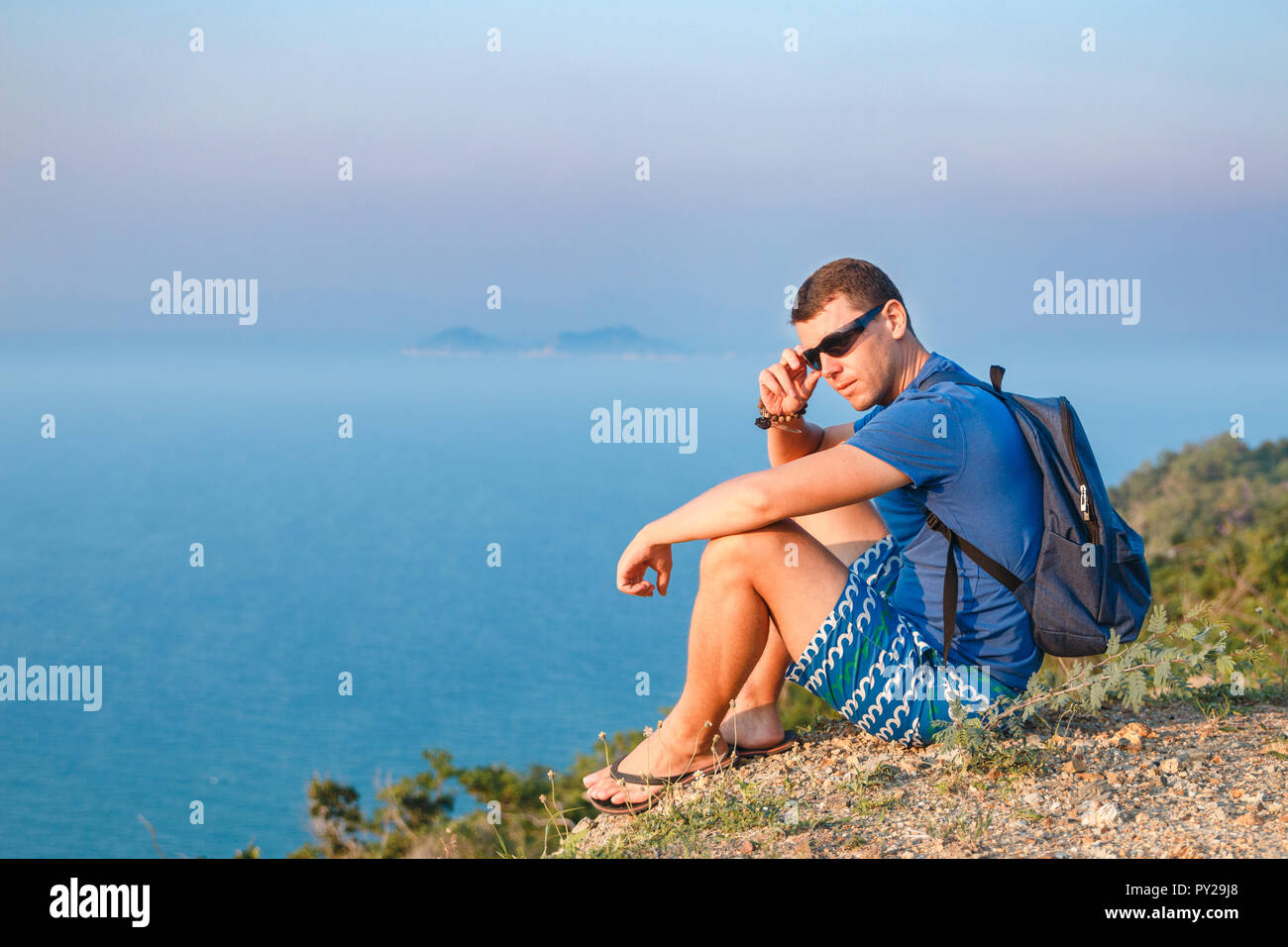 L'Homme à lunettes se trouve sur le bord d'une montagne. Banque D'Images