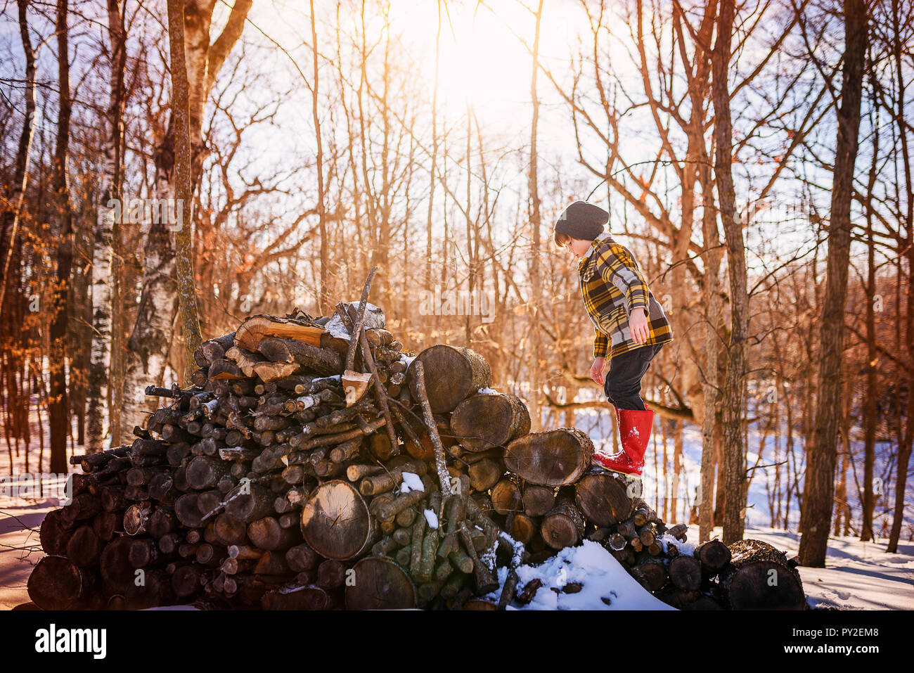 Garçon debout sur un tas de bois dans la neige, United States Banque D'Images