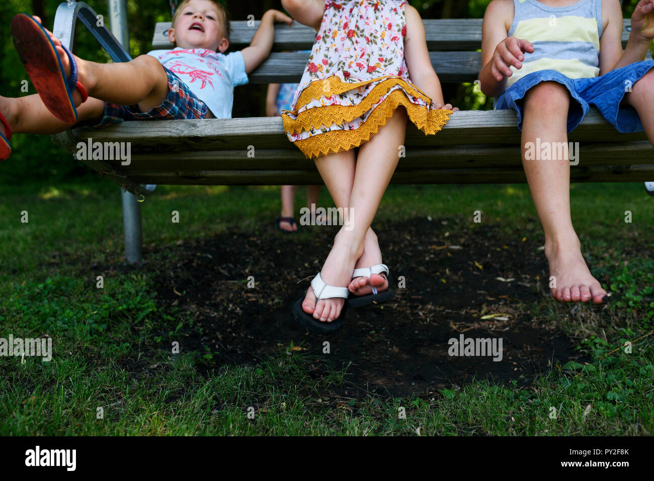 Trois enfants assis sur un porche swing Banque D'Images