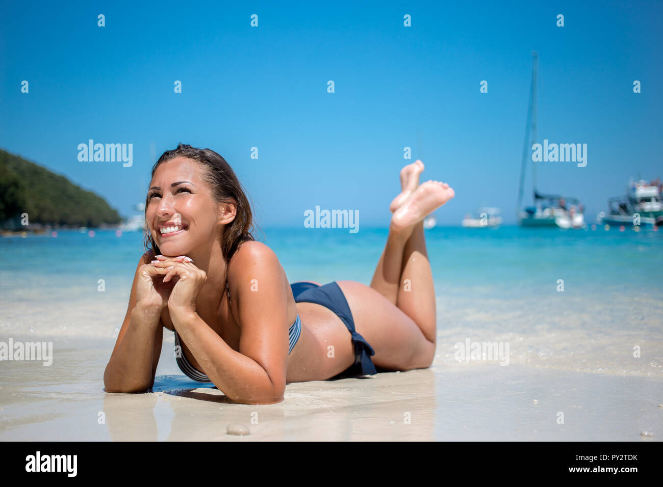 Belle jeune femme allongée sur la plage et souriant Photo Stock - Alamy