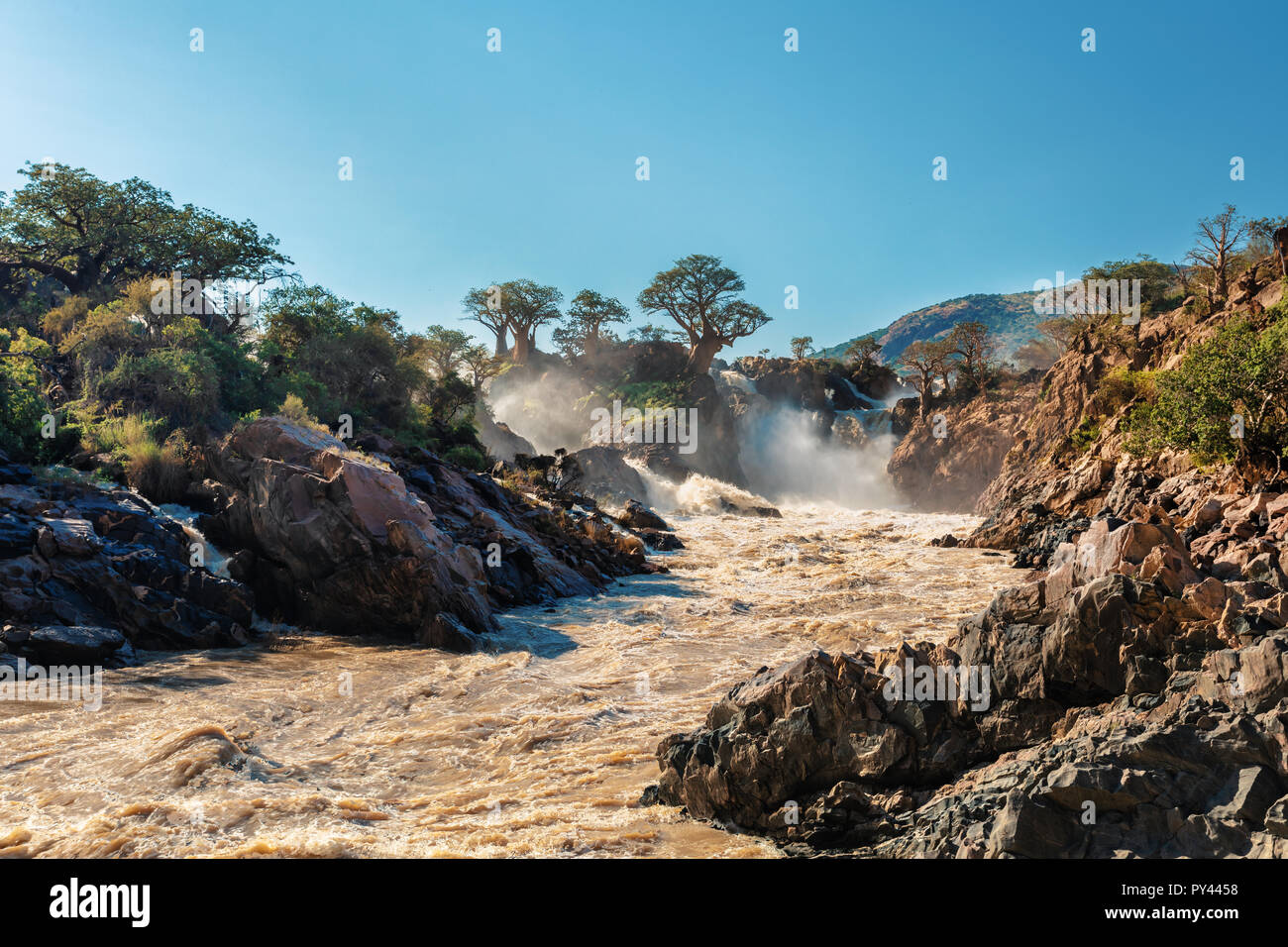 Epupa Falls célèbre sur la rivière Kunene au nord de la Namibie et du sud de l'Angola frontière. Lever du soleil la lumière du soleil dans l'eau de la brume. C'est l'Afrique. Magnifiques terres Banque D'Images