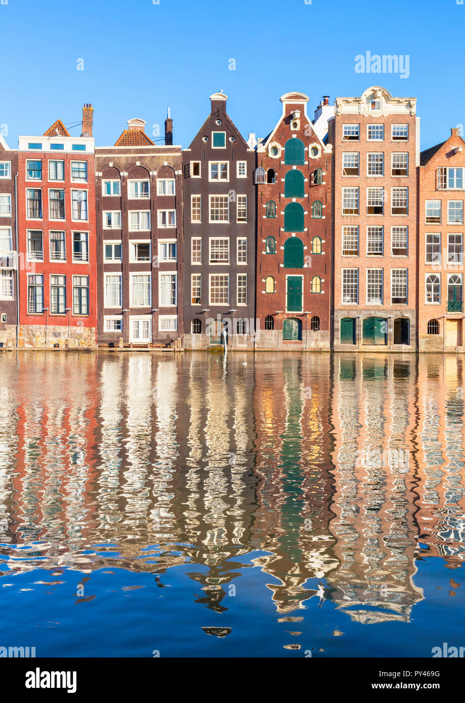 Maisons d'Amsterdam Damrak sur un canal partiellement remplies au dancing maisons avec l'architecture néerlandaise par le canal Amsterdam Hollande Pays-bas eu Europe Banque D'Images