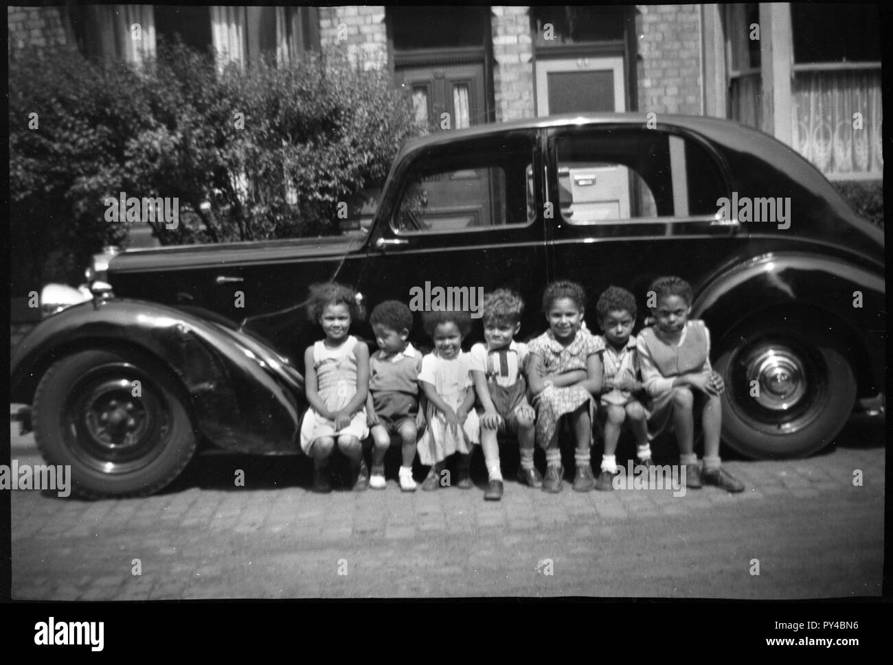 C1948 Black enfants posent sur le marchepied d'un véhicule immatriculé dans la région de Coventry de l'UK Photographie par Tony Henshaw Banque D'Images