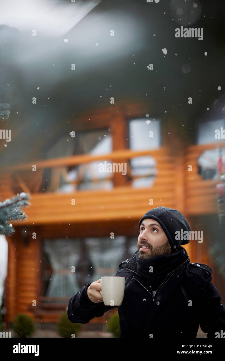 Homme avec boisson chaude à la neige qui tombe à Banque D'Images