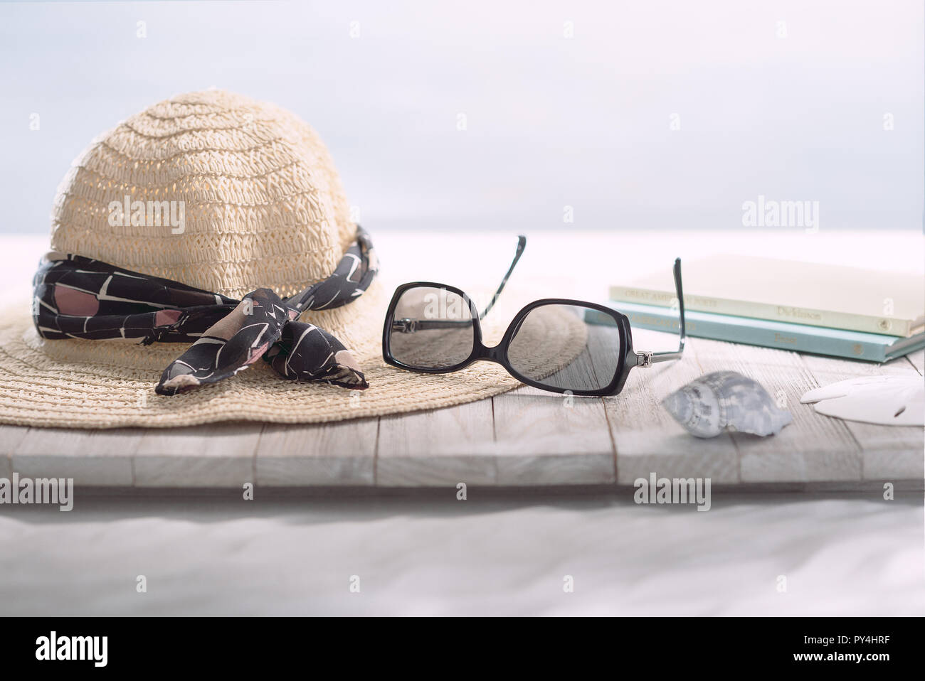 Scène de lecture à la plage avec chapeau et des lunettes de soleil. Banque D'Images