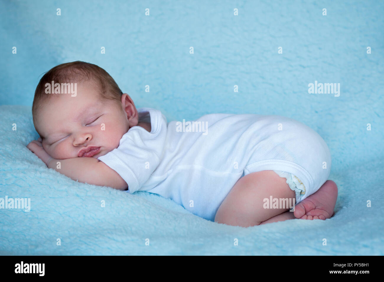 Bébé nouveau-né de dormir sur le ventre toute la longueur du profil latéral arrière-plan bleu Banque D'Images