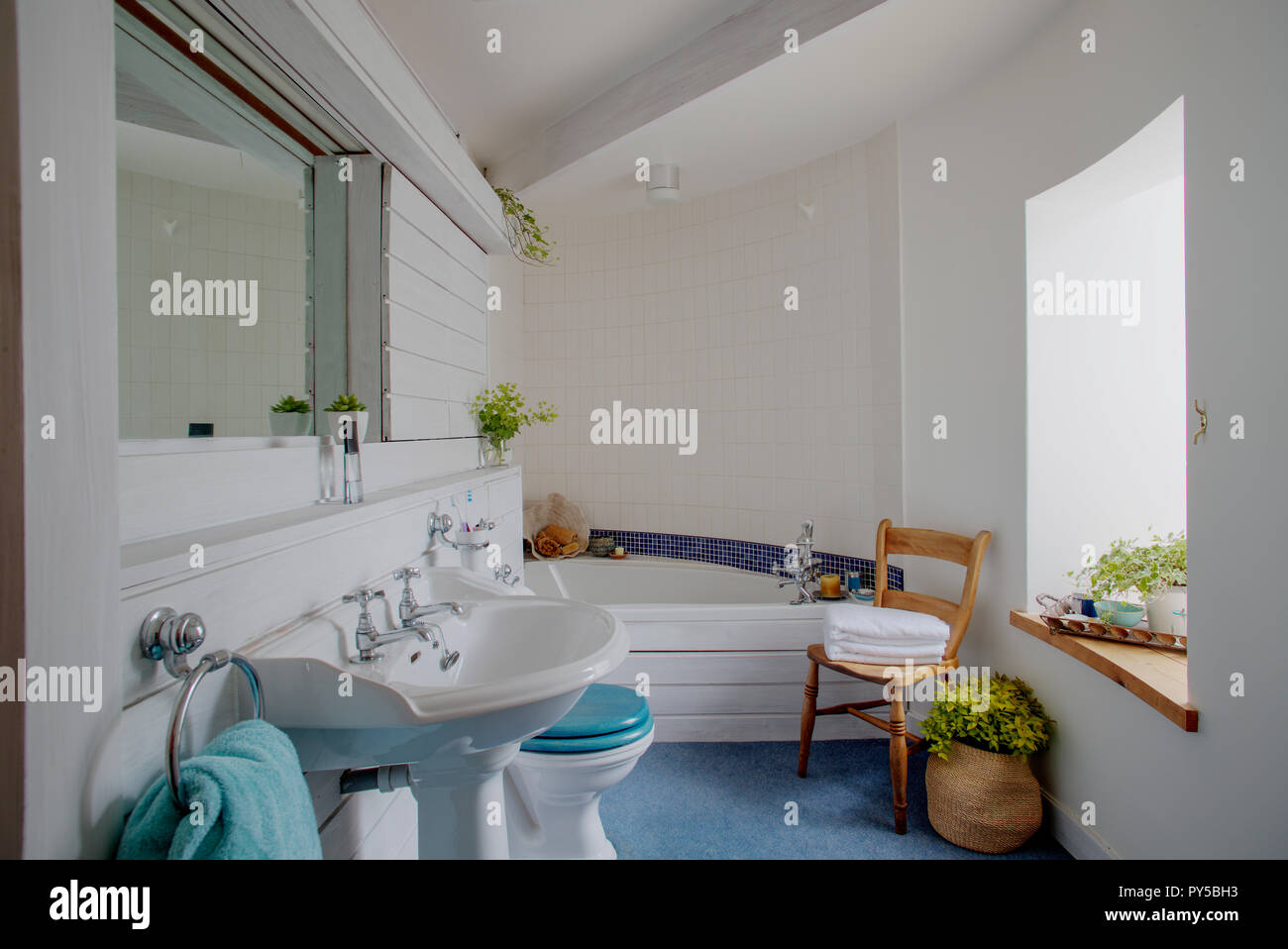 Une large vue tourné d'une élégante salle de bains de l'intérieur, un motif en mosaïque bleu traverse le mur carrelé au-dessus de la baignoire à l'arrière de la salle. Banque D'Images