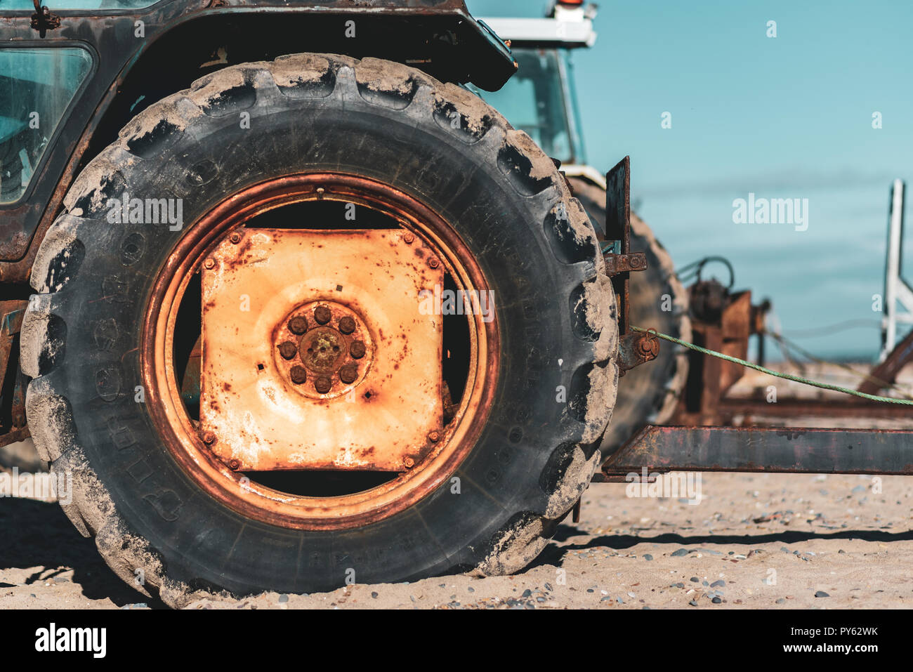 Un vieux rusty la roue du tracteur sur la plage Banque D'Images