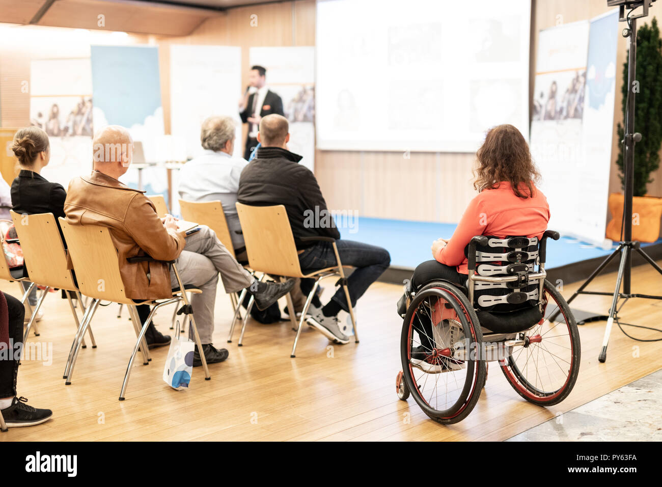 Vue arrière du nrecognizable femme sur un fauteuil roulant qui participent à des discours de conférence. Banque D'Images