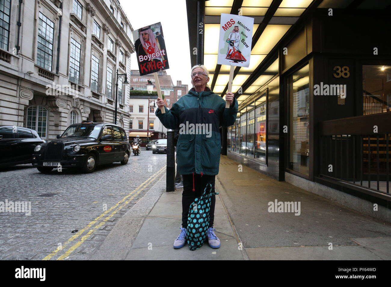 Une femme est titulaire d'une affiche (à droite) dénoncer l'Arabie Prince Mohammed bin Salman sur la mort du journaliste Jamal Khashoggi, lors d'une manifestation devant l'ambassade d'Arabie saoudite, au centre de Londres. Banque D'Images