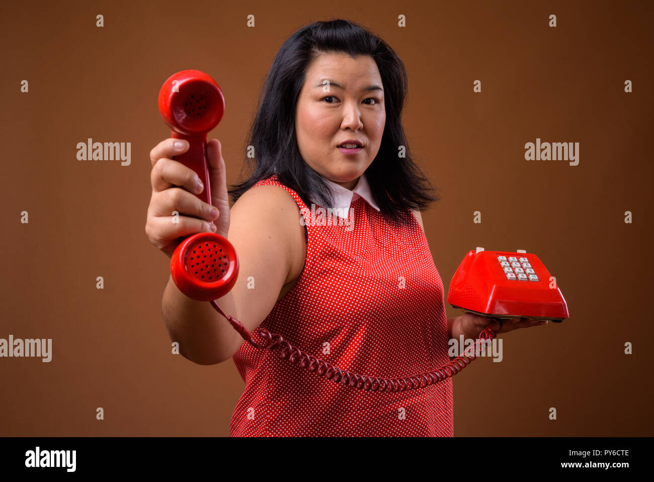 Belle femme asiatique en surpoids donnant old red phone Banque D'Images