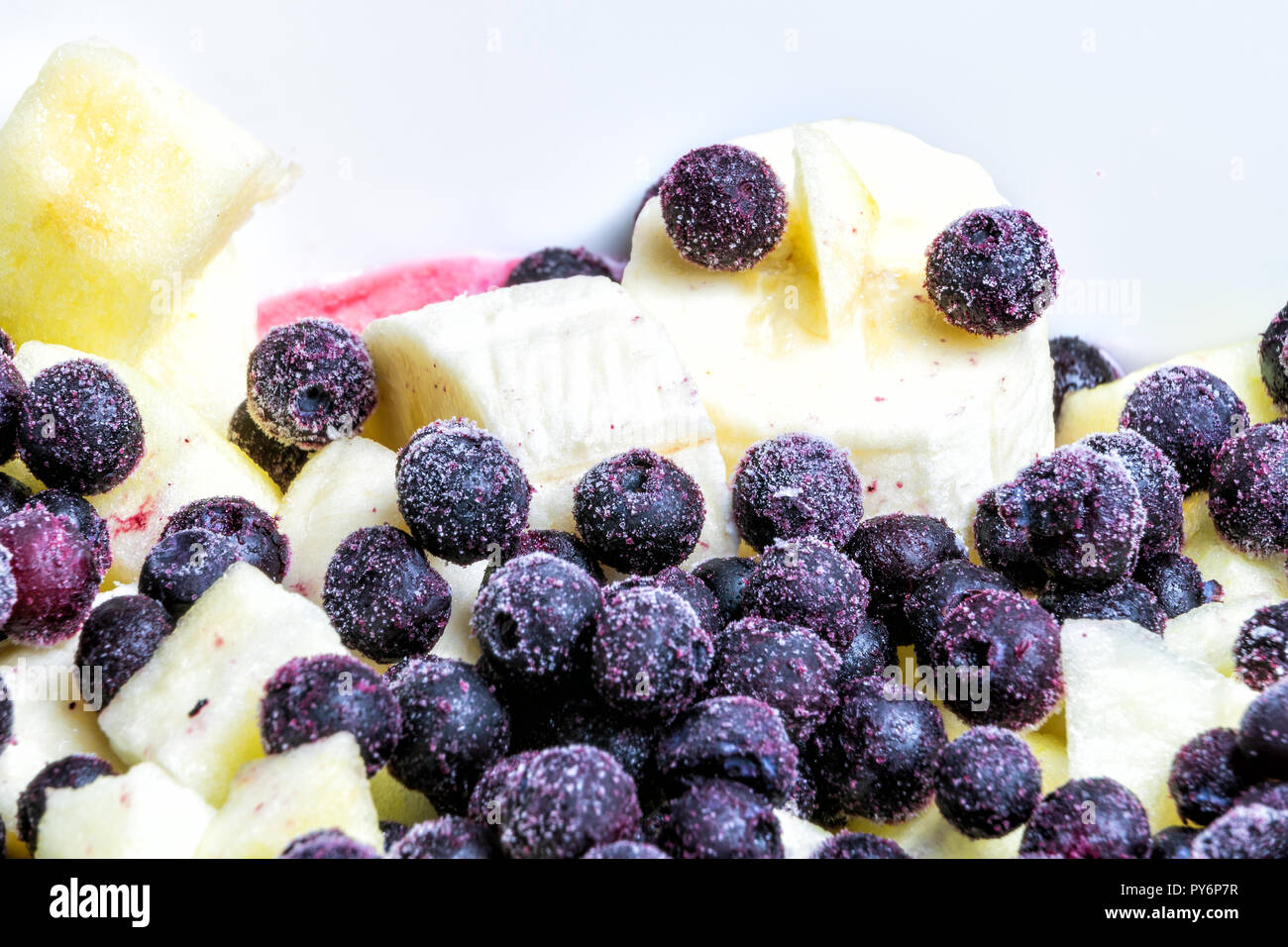 Gros plan macro de la salade de fruits dans un bol avec les baies congelées, bleuet, myrtille, banane, pommes Banque D'Images