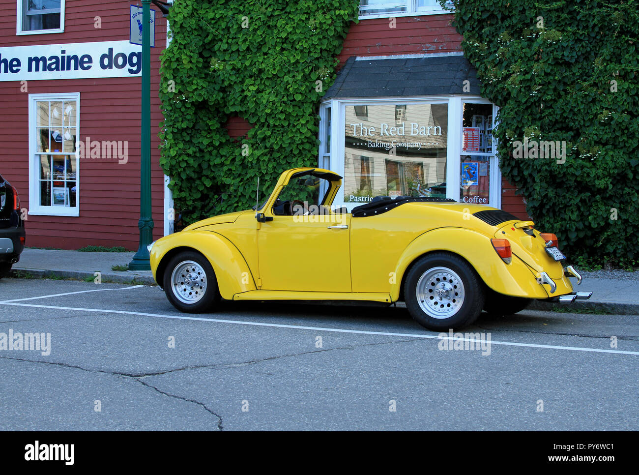 Un magnifique bâtiment restauré Volkswagen Beetle convertible jaune garée dans une rue latérale à Camden, Maine, en face de certains magasins Banque D'Images