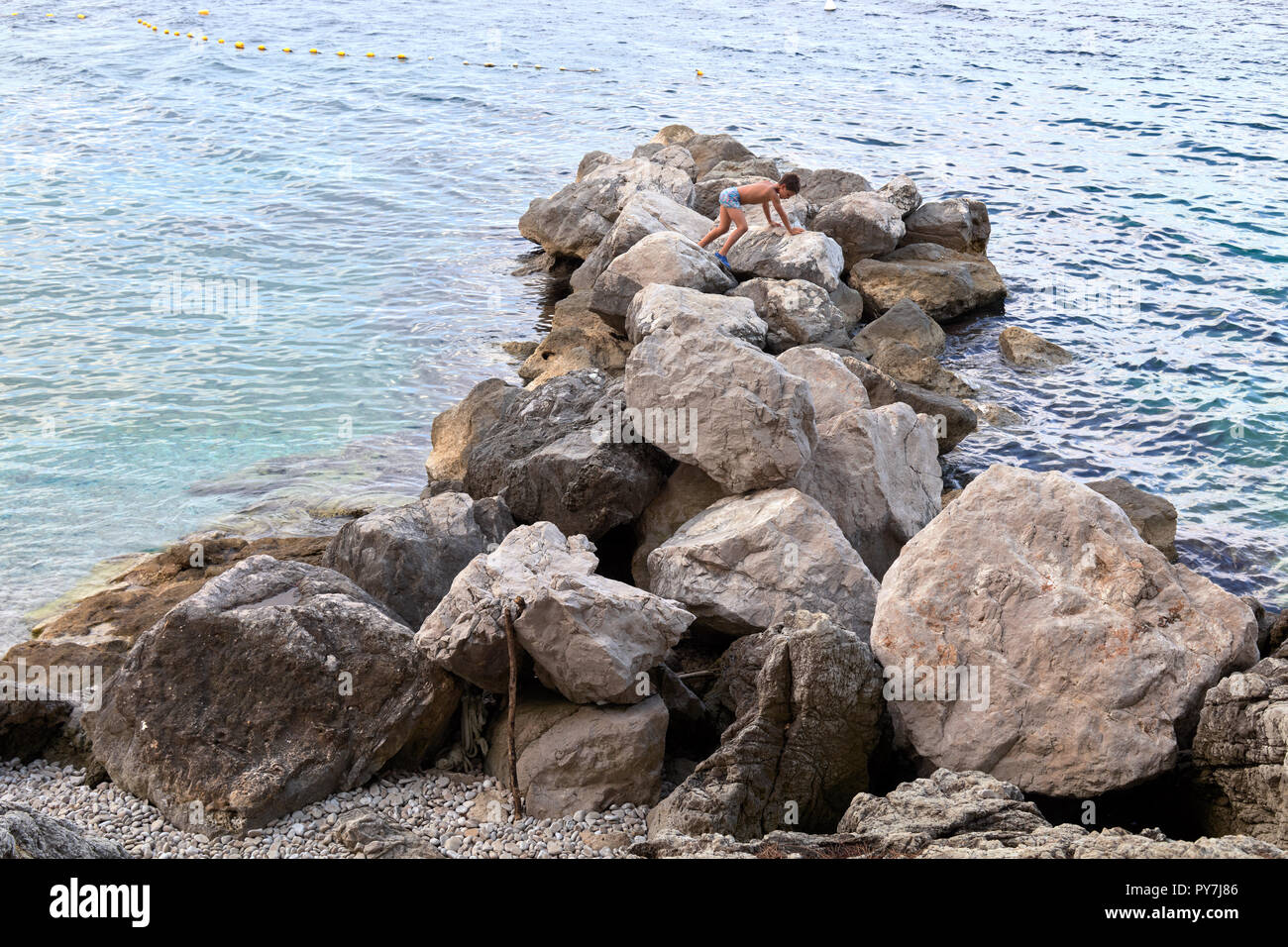Enfant jouant en grimpant sur un rocher à Moscenicka Draga, Istrie, Croatie Banque D'Images