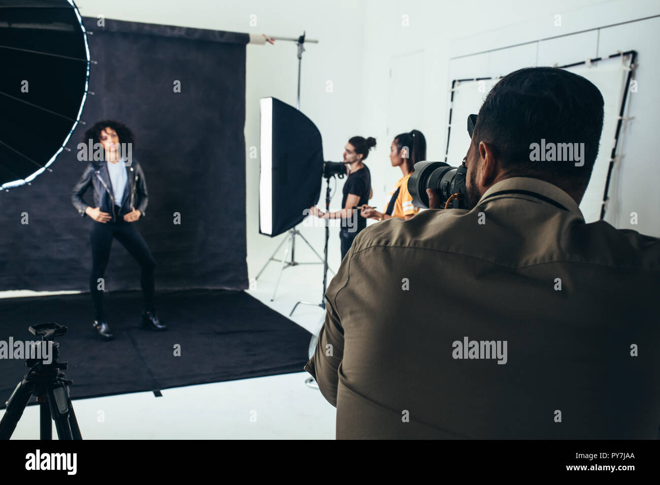 Photos de tournage photographe un modèle dans un studio avec son équipage holding studio flash lights. Banque D'Images