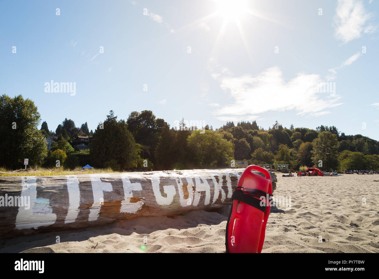 Une bouée de sauvetage dans le sable en face d'un log avec lifeguard written on it Banque D'Images