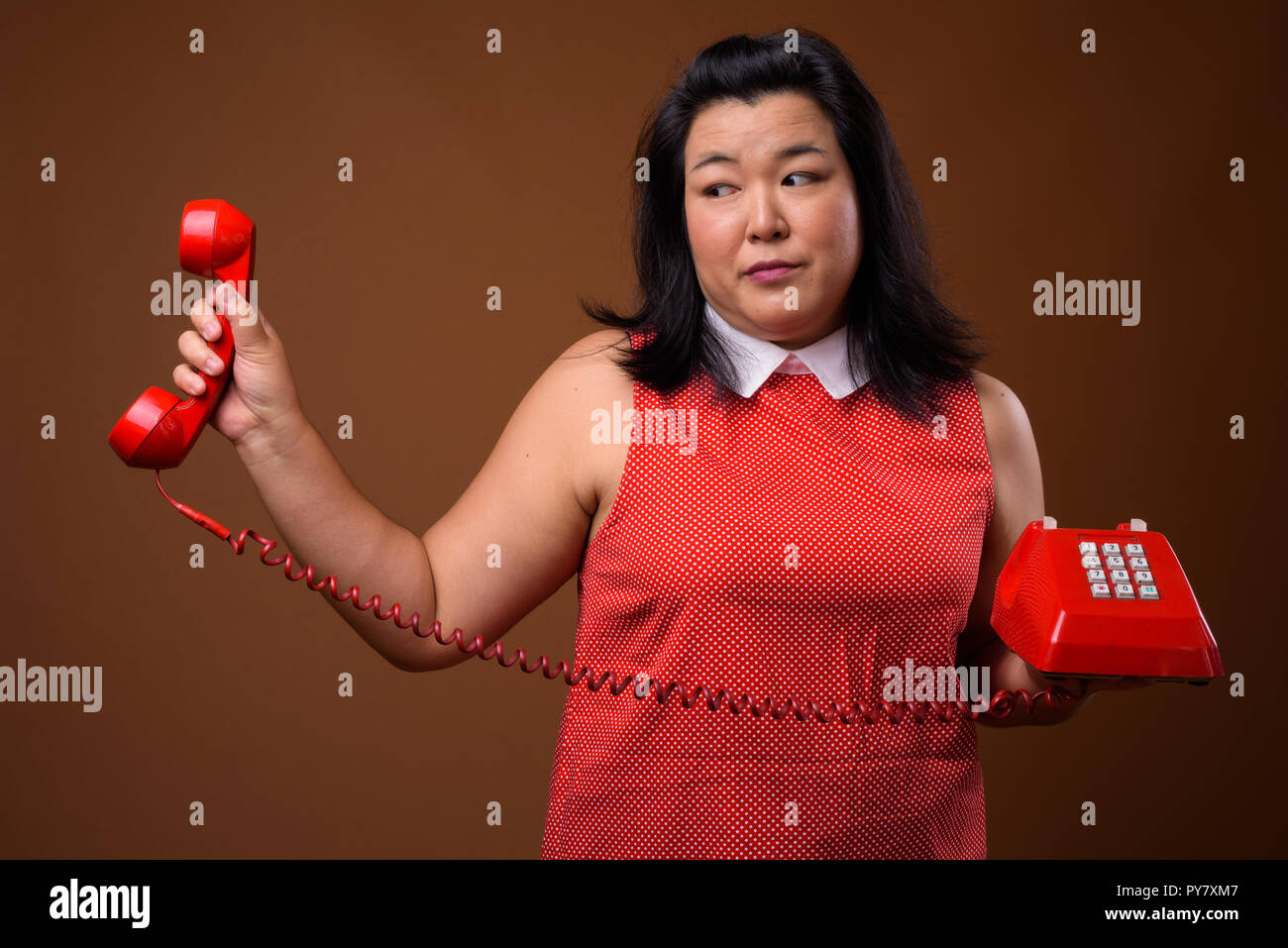 Ennuyer surpoids Asian woman holding old red phone Banque D'Images