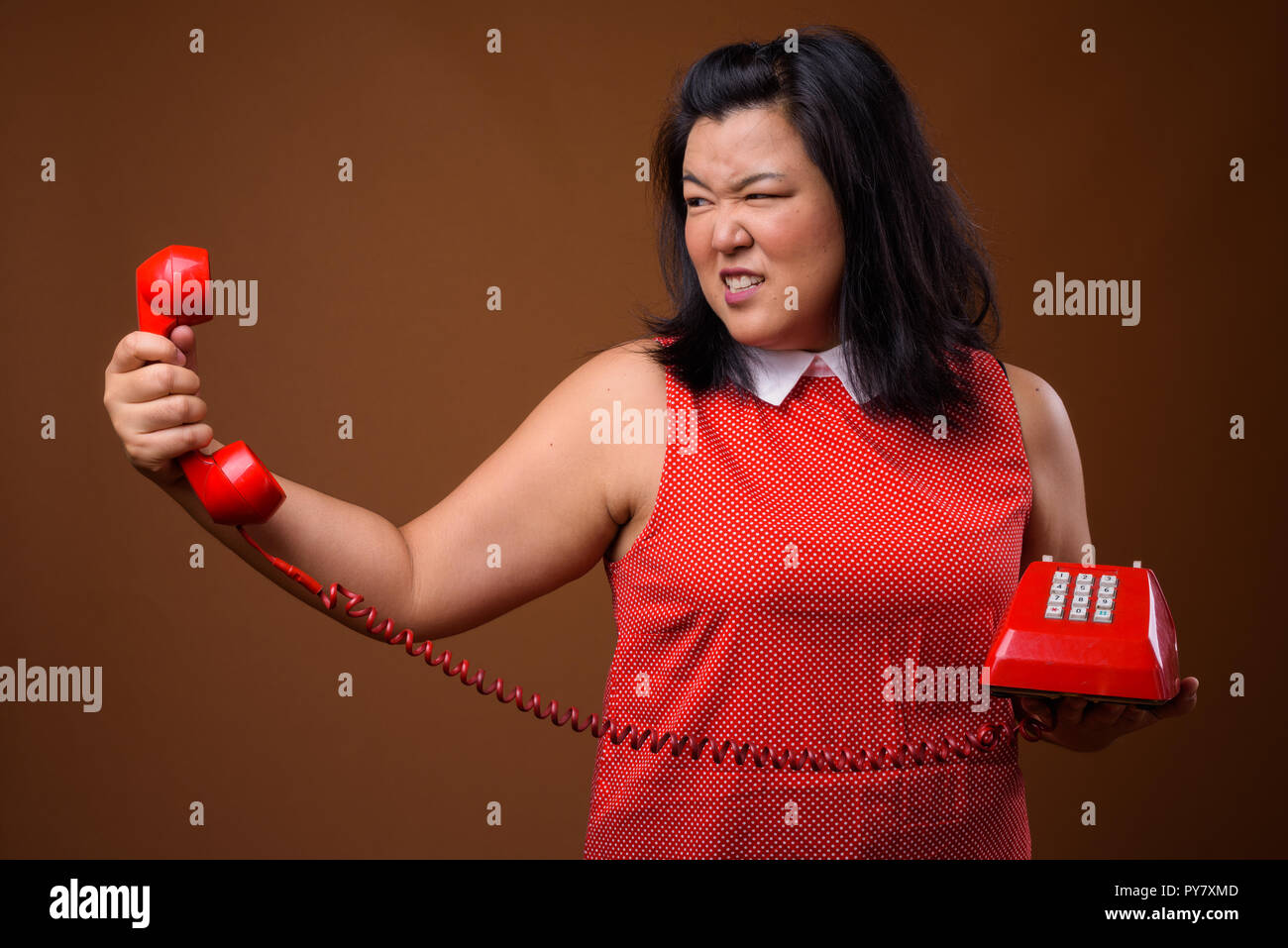L'excès de colère Asian woman holding old red phone Banque D'Images