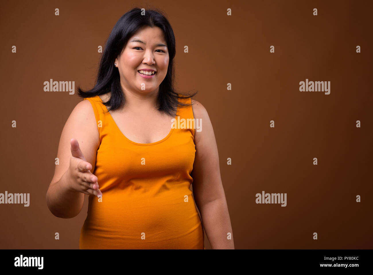 Belle femme asiatique de poids poignée donnant accord pour Banque D'Images