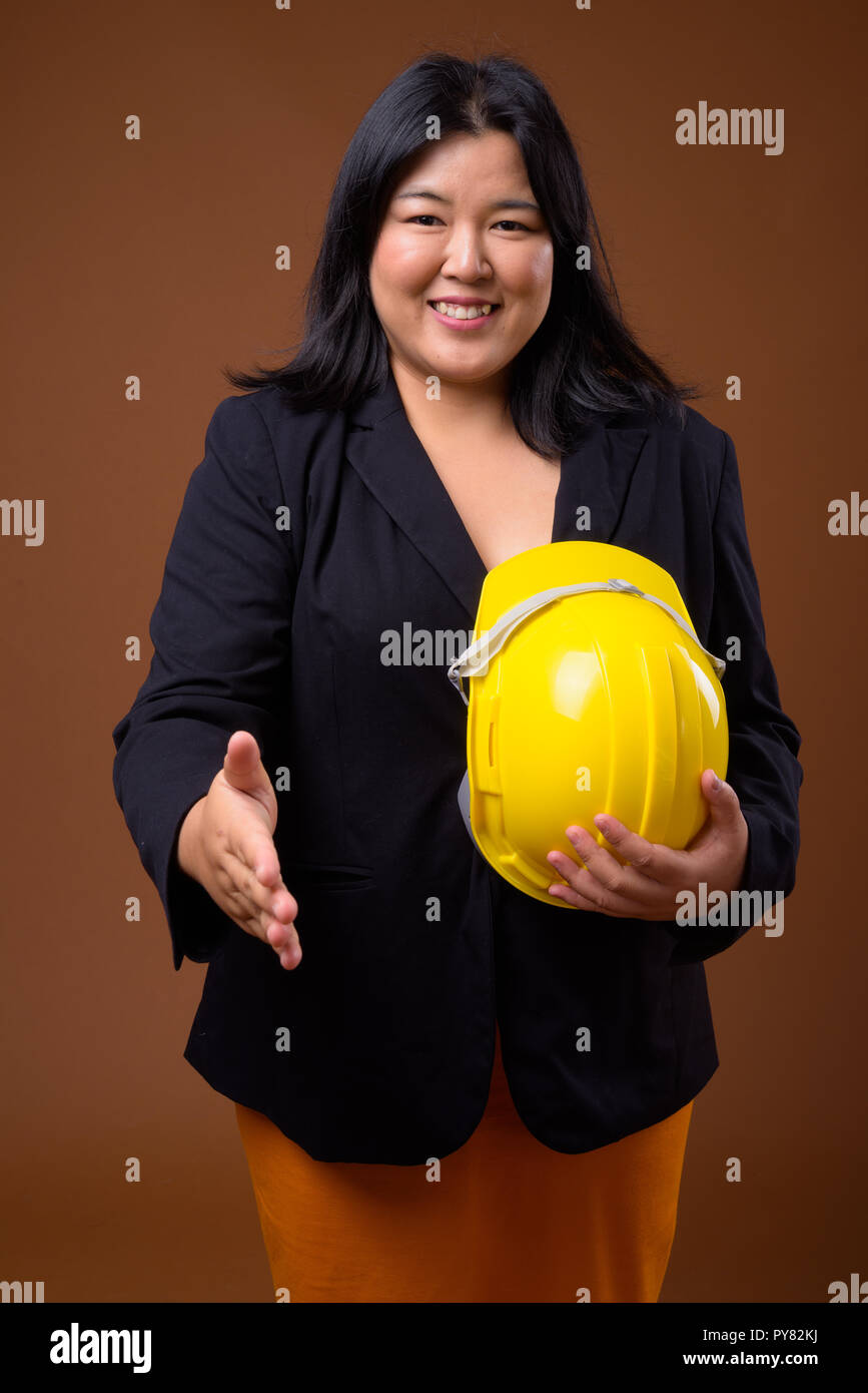 Happy Asian businesswoman holding casque de protection et poignée offrant Banque D'Images